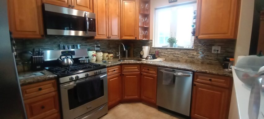 Modern kitchen with wooden cabinetry, stainless steel appliances, and granite countertops.