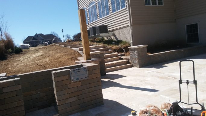 Path with stone steps leading to a grassy area beside a building.